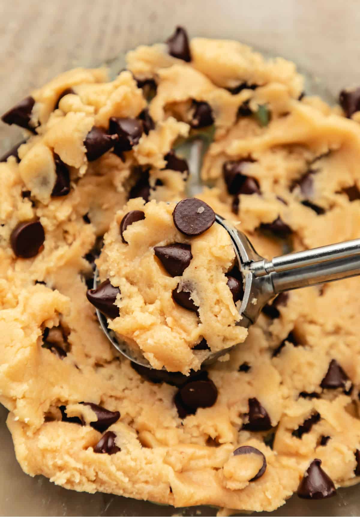 A cookie scoop holding a scoop of chocolate chip cookie dough. 