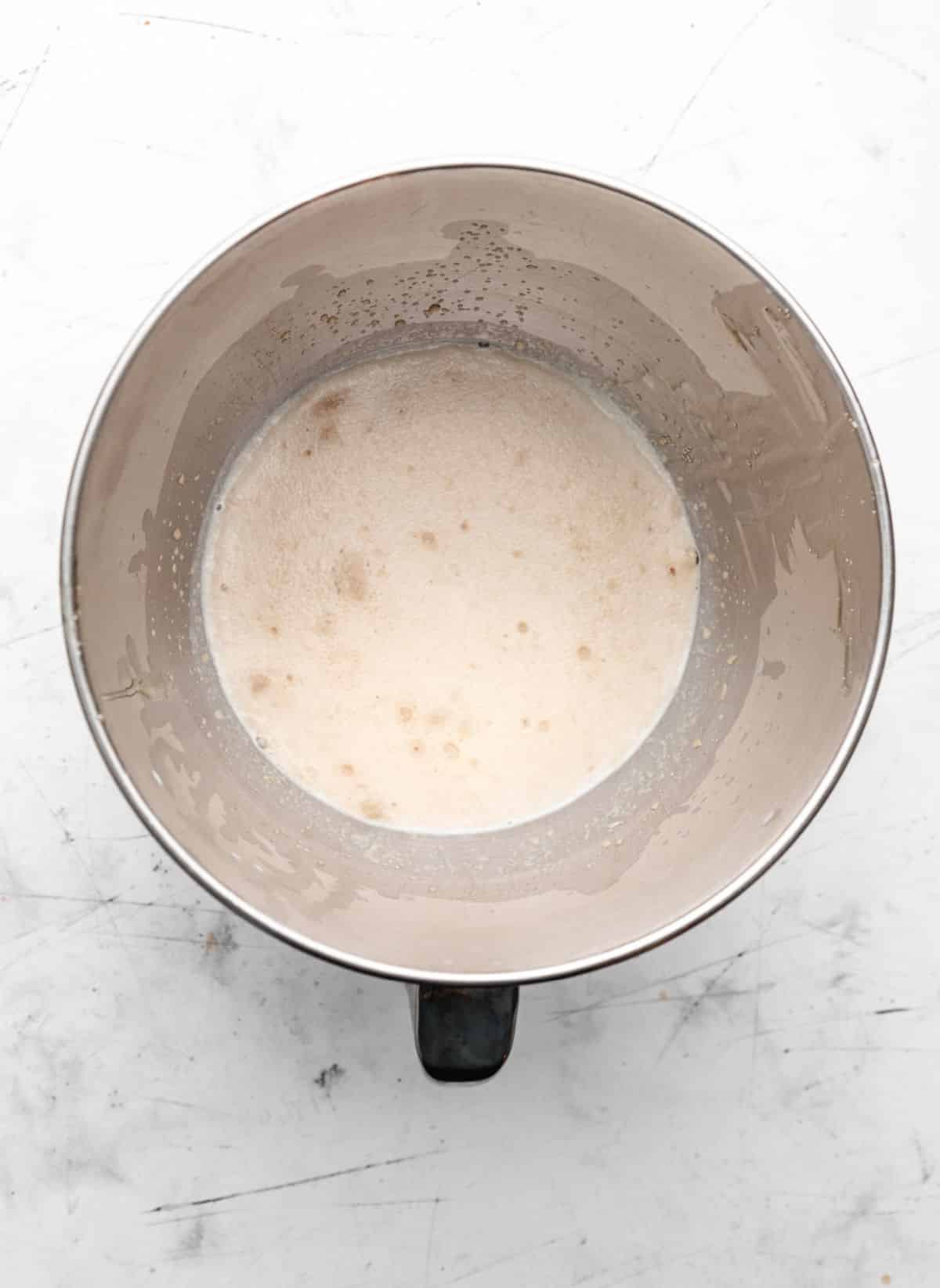 Milk yeast and honey in a mixing bowl. 