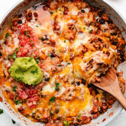 A wooden spoon holding a scoop of Mexican ground beef and rice.