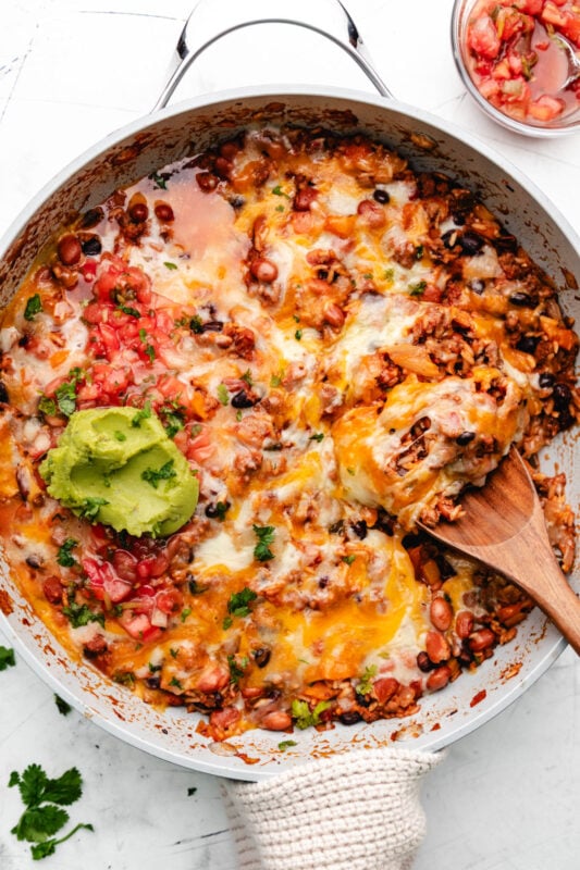 A wooden spoon holding a scoop of Mexican ground beef and rice.