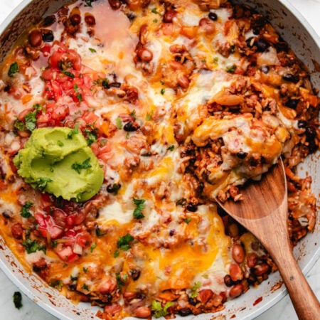A skillet of Mexican ground beef and rice with a wooden spoon in it.