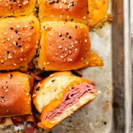 A baked roast beef slider on its side next to more sliders.