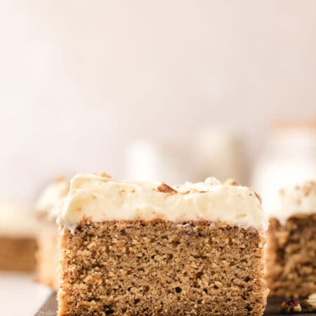 Slices of banana sheet cake on a wooden cutting board.