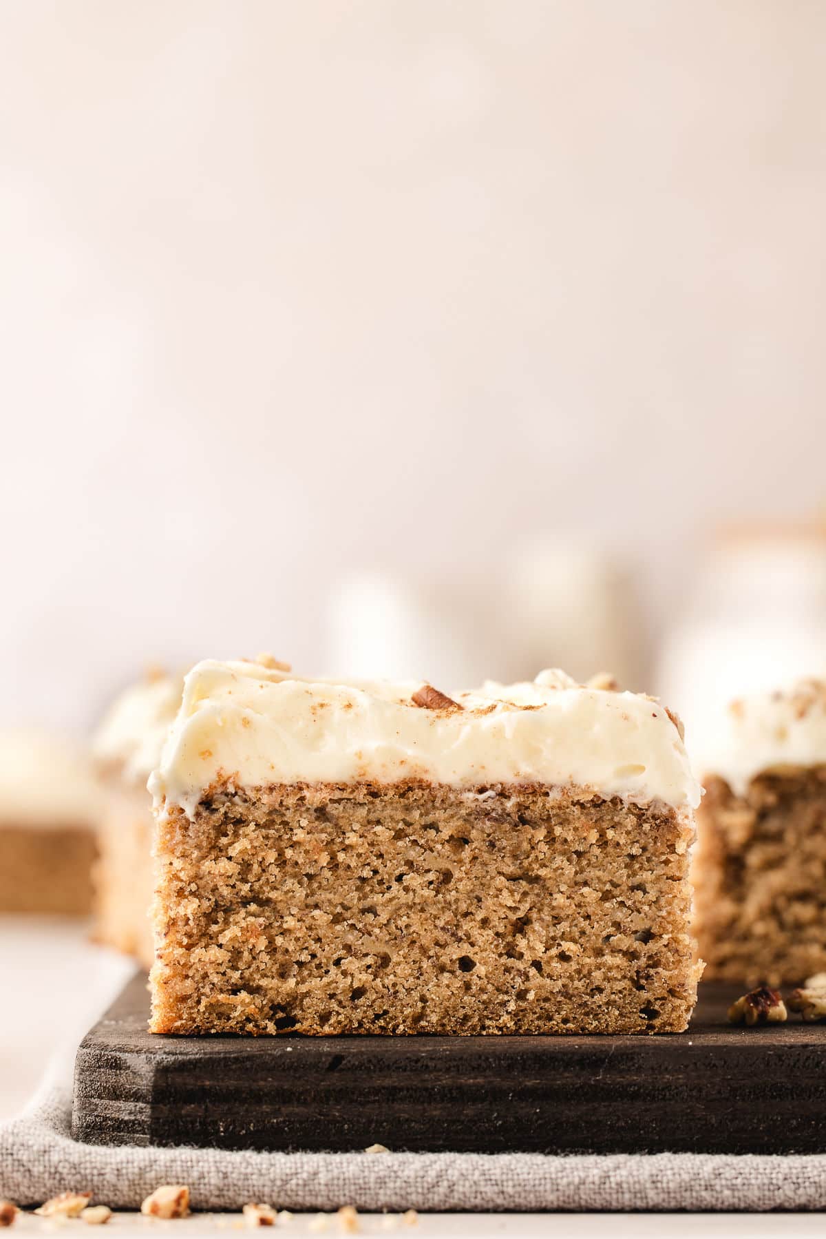 Slices of banana sheet cake on a wooden cutting board.