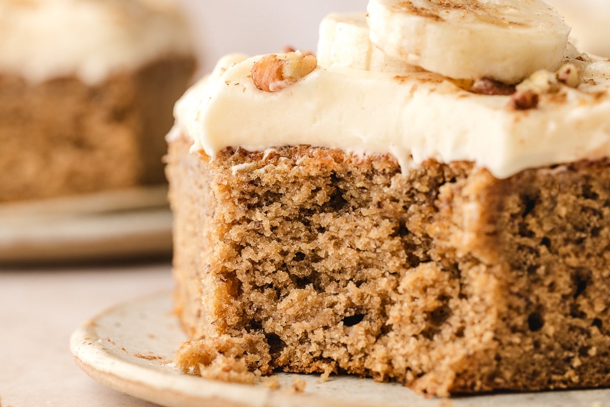 Banana Cake with Cream Cheese Frosting A piece of banana cake with cream cheese frosting with a bite missing.