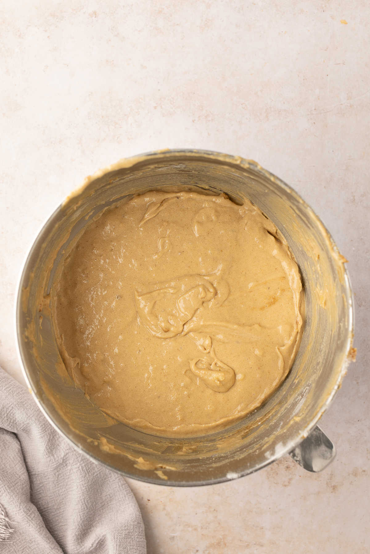 Banana cake batter in a silver mixing bowl.