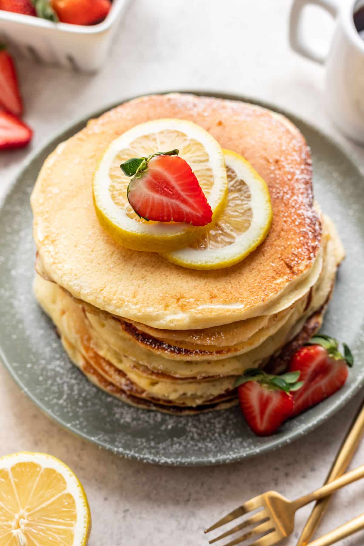 Blueberry Lemon Ricotta Pancakes A stack of lemon ricotta pancakes next to a dish of strawberries.