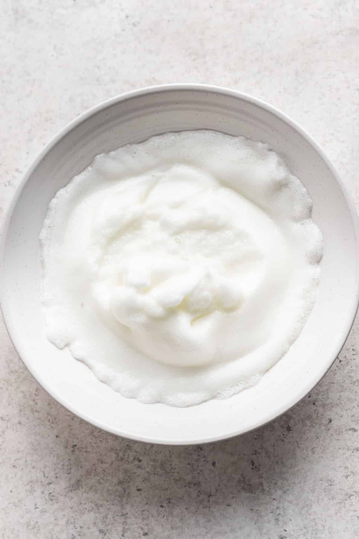 Soft peak egg whites in a mixing bowl.