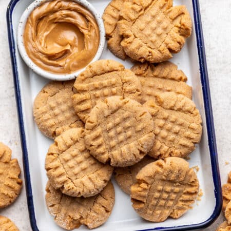 Peanut butter cookies in a baking dish next to a dish of peanut butter.