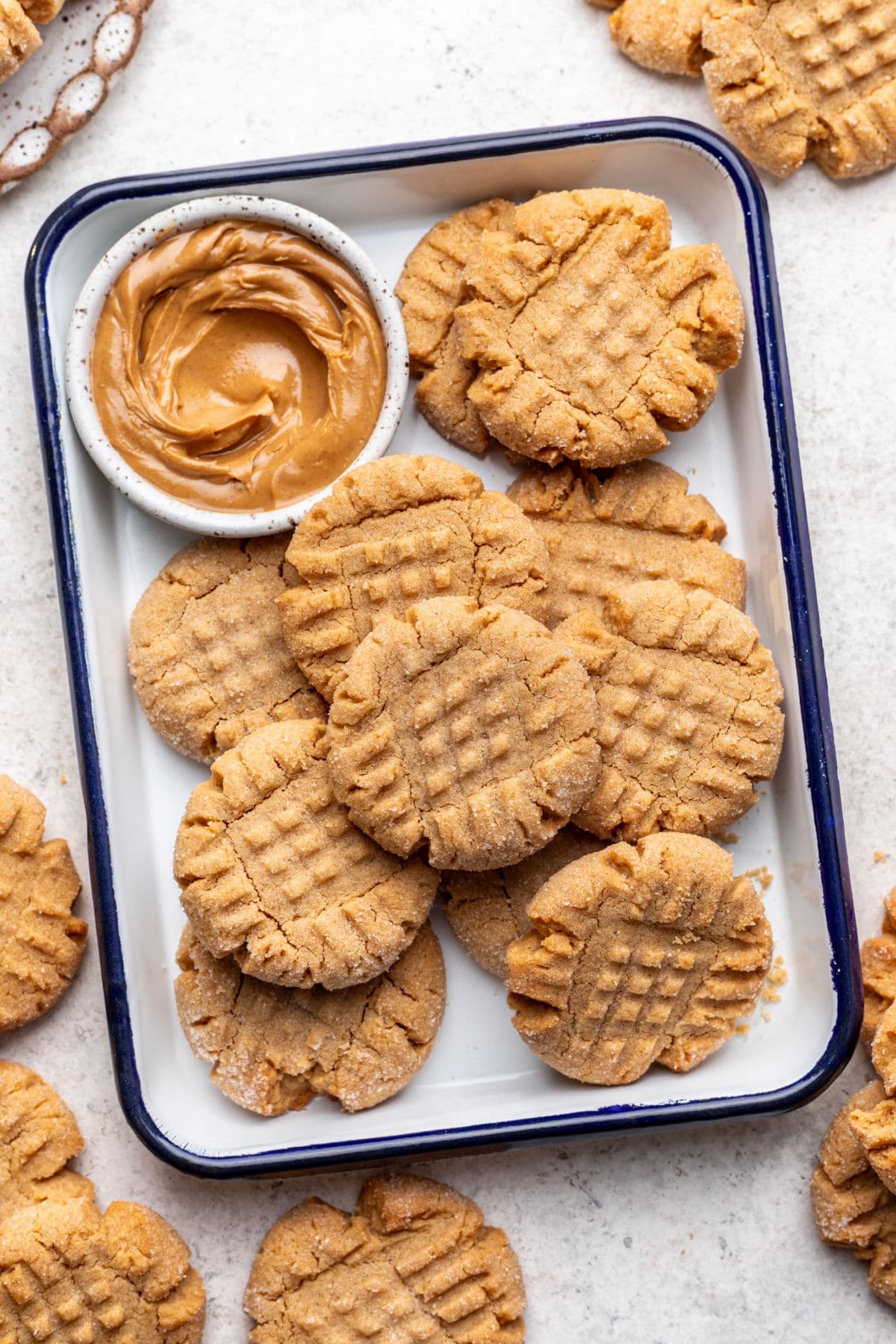 Peanut butter cookies in a baking dish next to a dish of peanut butter.