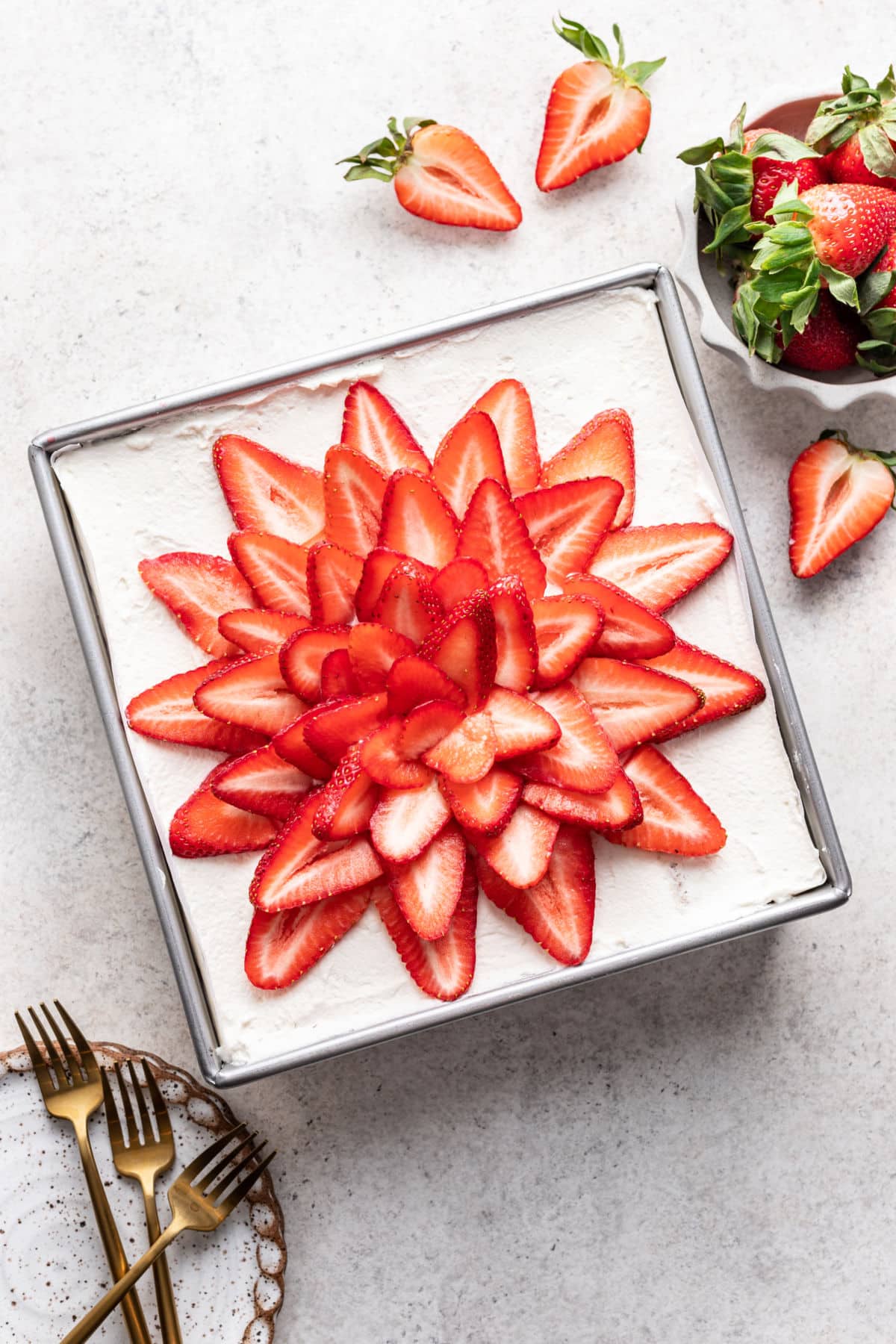Strawberry icebox cake in a pan next to a dish of fresh strawberries. 