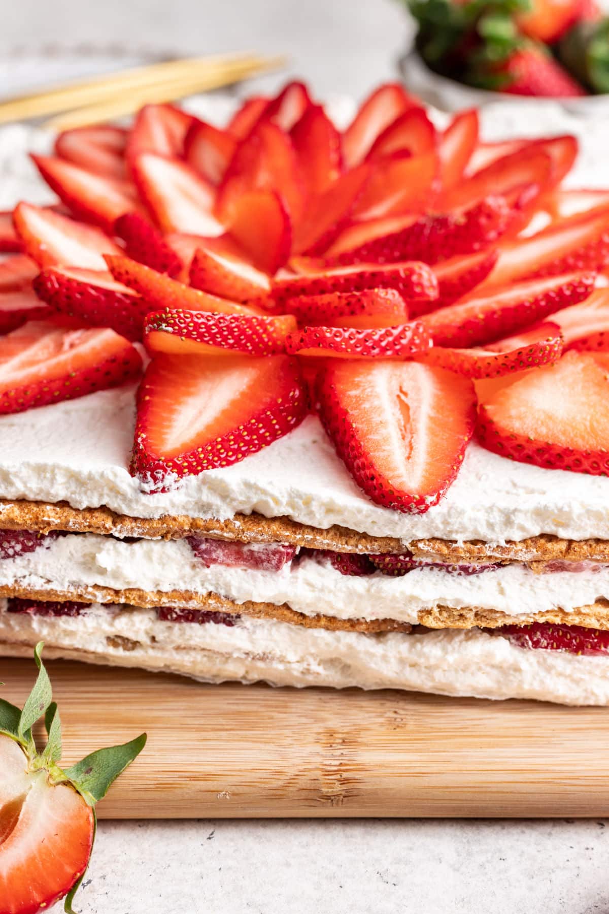 A strawberry icebox cake on a wooden cutting board.