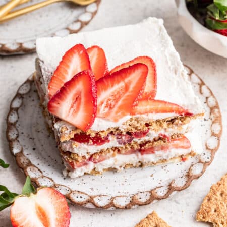 A slice of strawberry icebox cake next to three gold forks.
