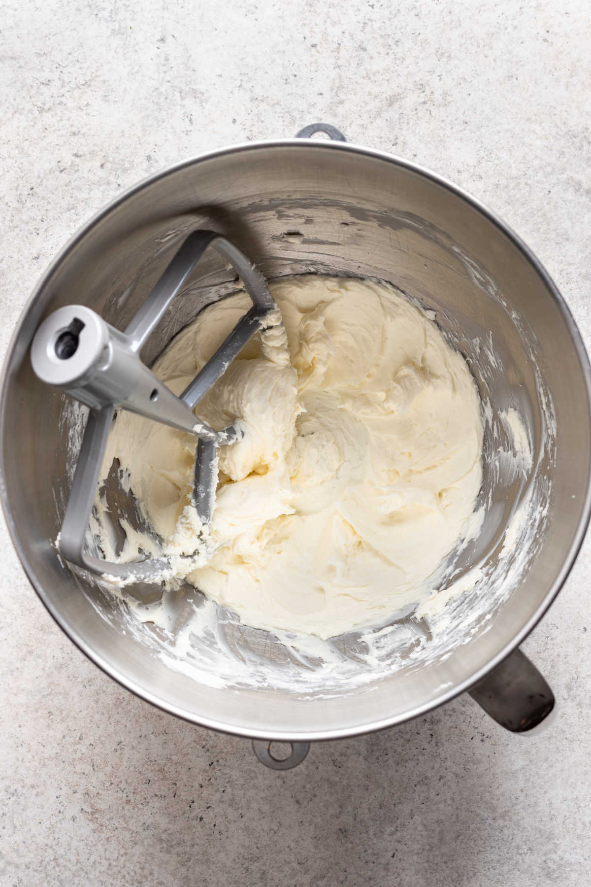 Beaten cream cheese in a silver mixing bowl. 