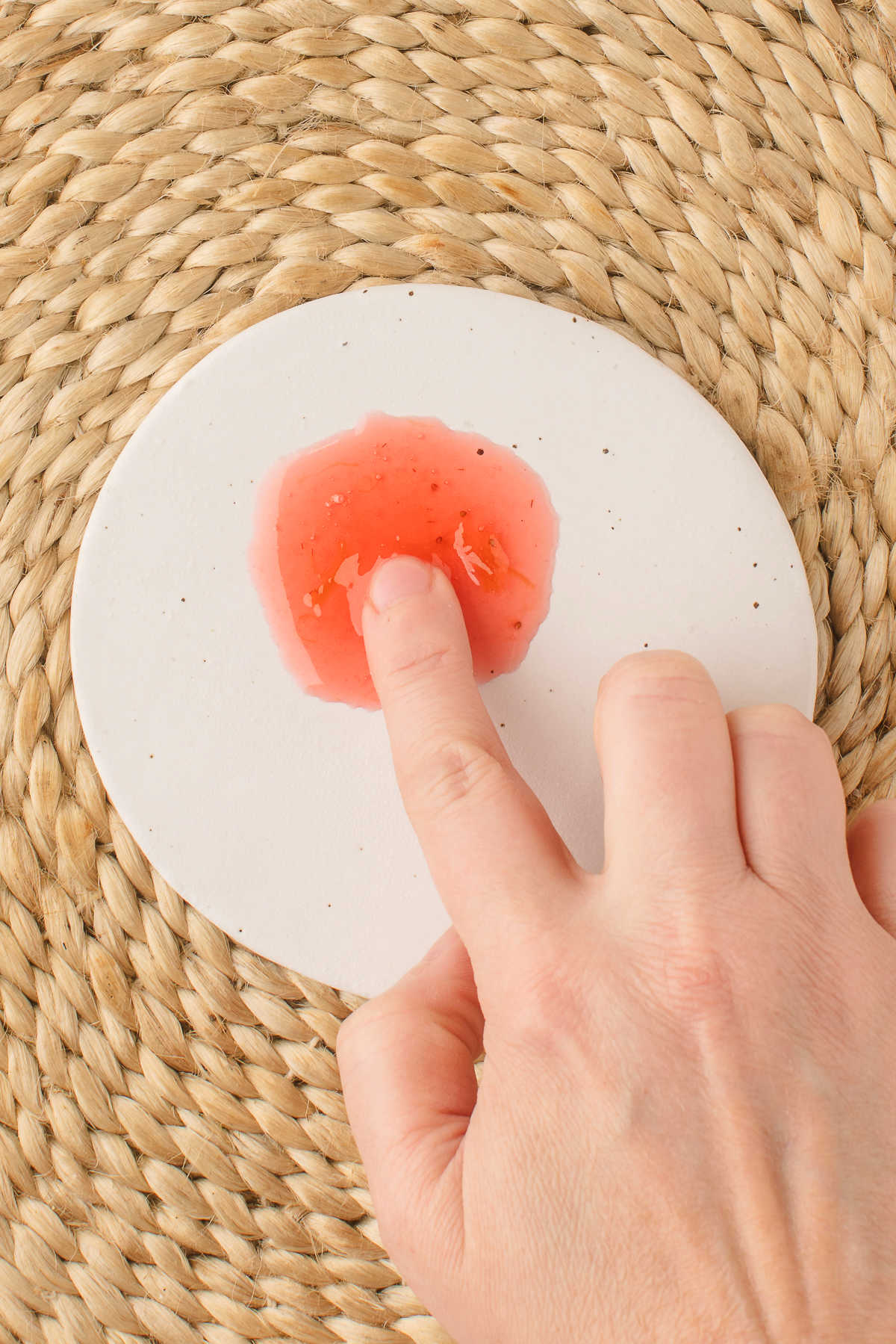 A finger dragging through strawberry rhubarb jam on a plate.