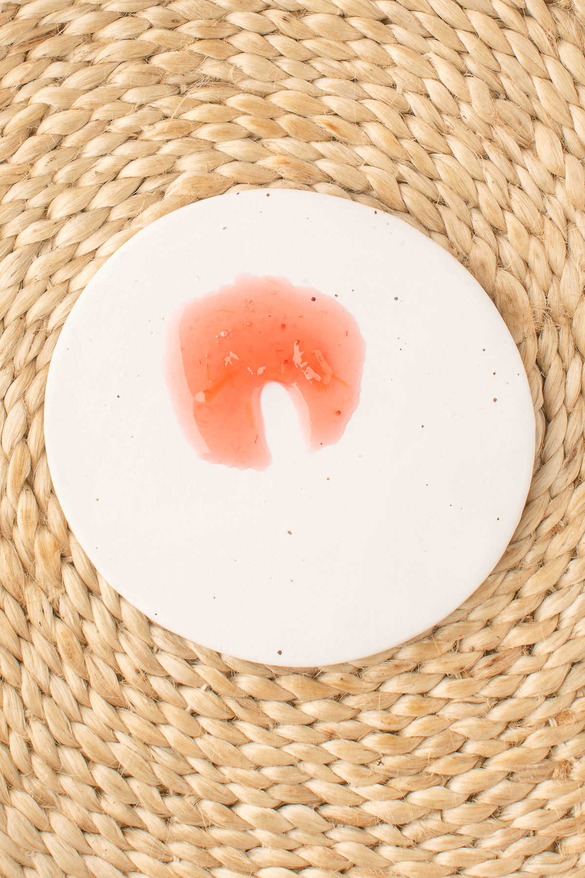 Strawberry rhubarb jam on a plate with a dent in it. 