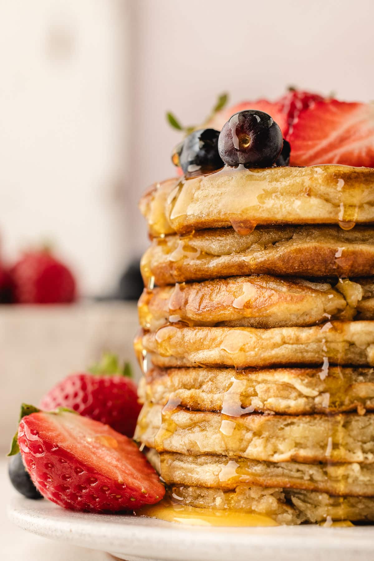 Maple syrup pouring down a stack of sweet cream pancakes.