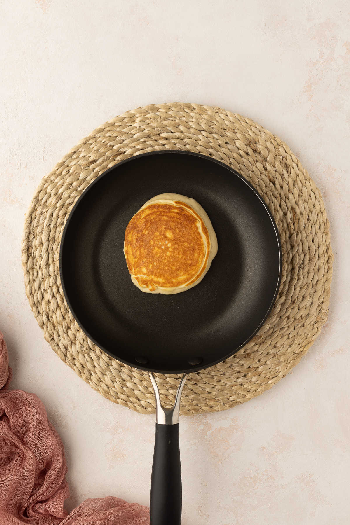 A sweet cream pancake cooking in a skillet.