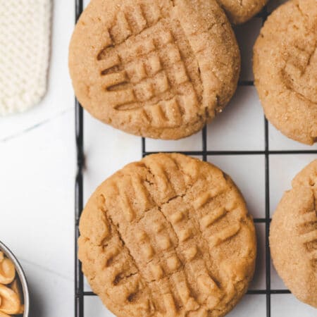 Overlapping peanut butter cookies on a black metal cooling rack.