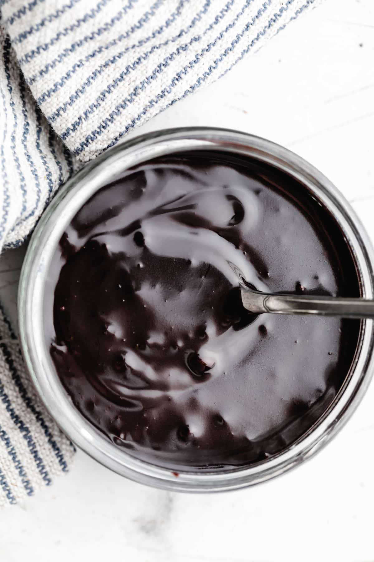 Vanilla extract stirred into a jar of homemade hot fudge sauce.