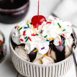 Homemade hot fudge on scoops of vanilla ice cream with whipped cream and a cherry on top.