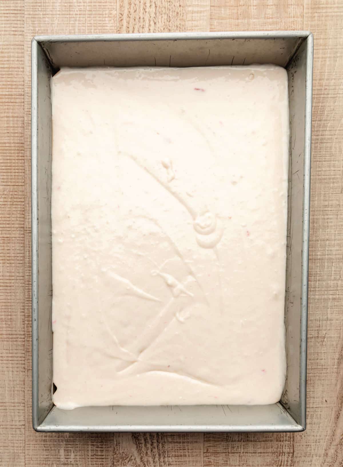 Strawberry yogurt cake batter in a 9 by 13 pan. 