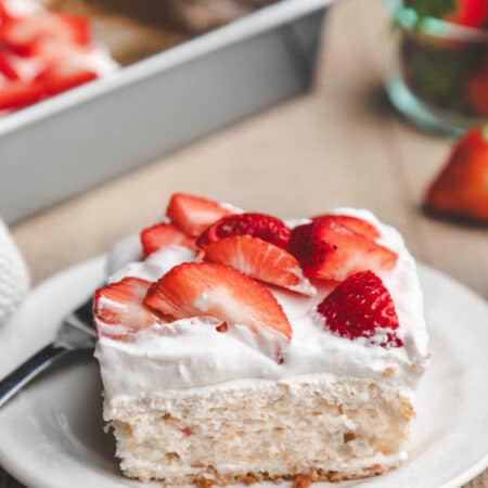 A plate of strawberry yogurt cake next to a bowl of fresh strawberries.