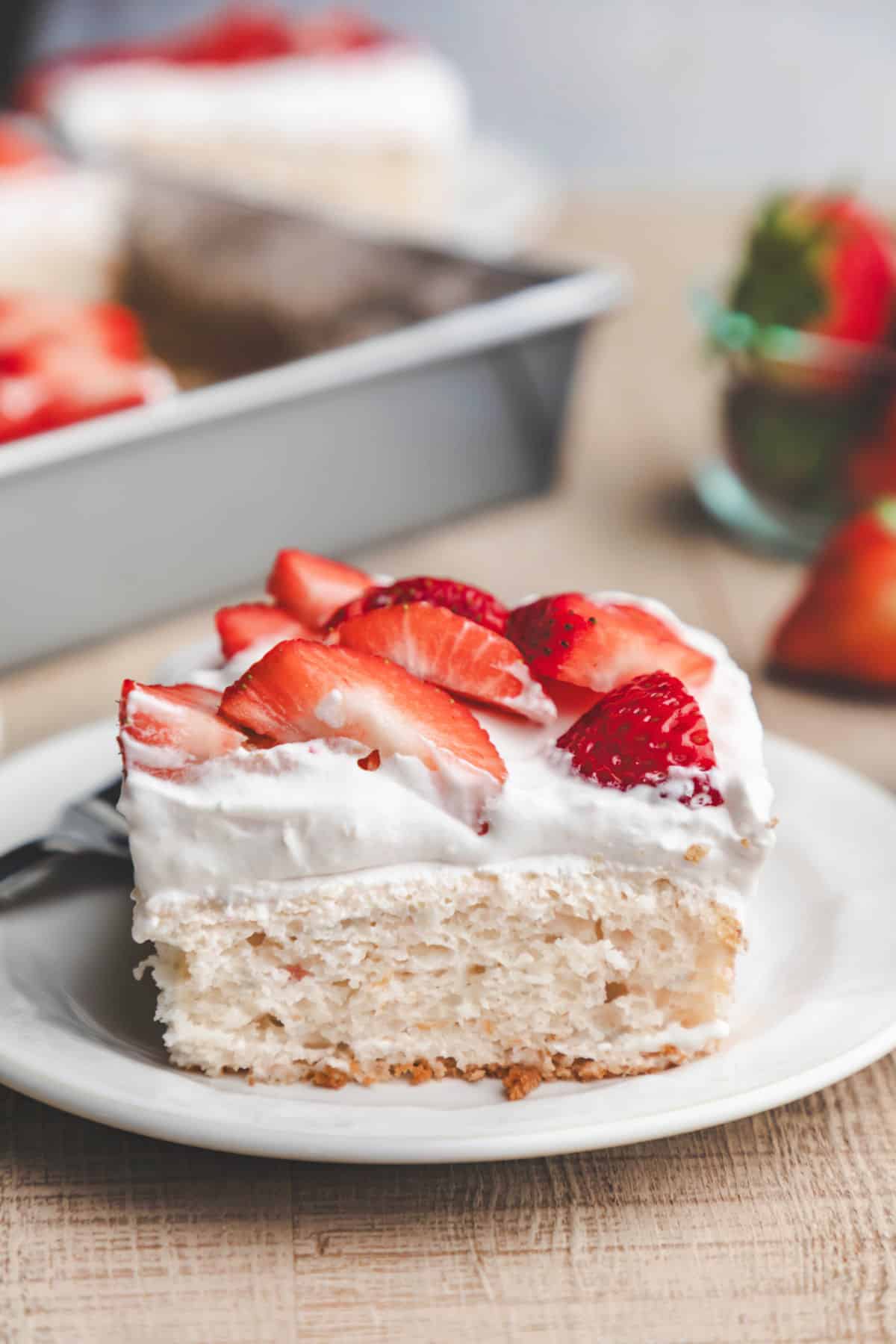 A slice of strawberry yogurt cake topped with fresh strawberry slices.