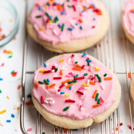 A row of pink frosted Lofthouse copycat cookies on a wire cooling rack.