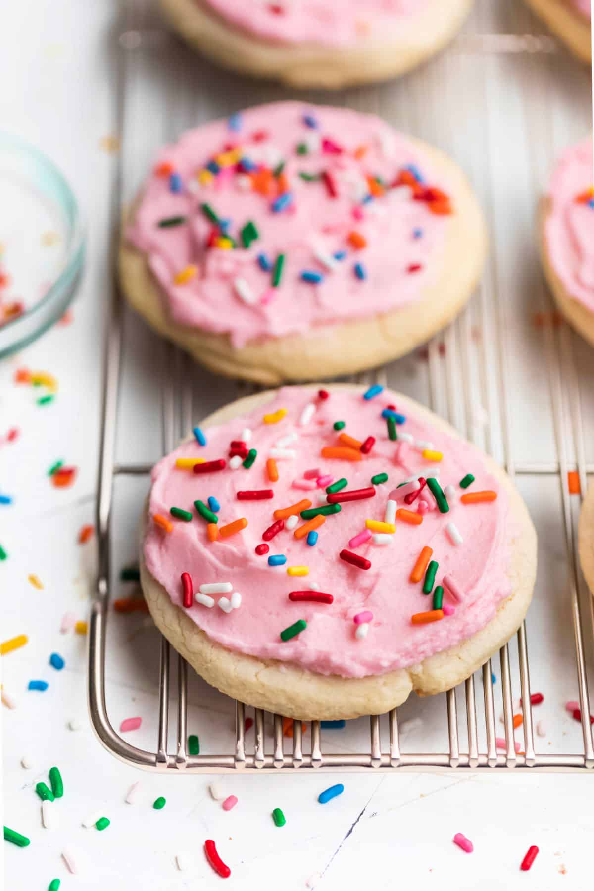 Lofthouse Sugar Cookie Recipe A row of pink frosted Lofthouse copycat cookies on a wire cooling rack.