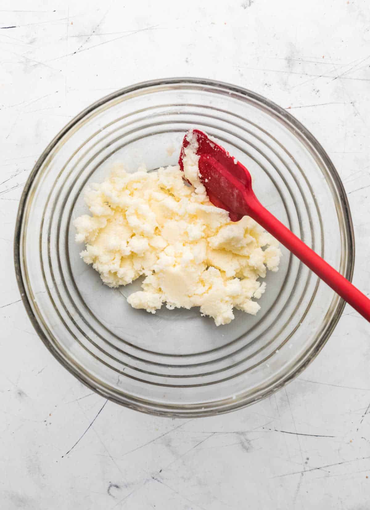 Creamed butter and sugar mixture in a glass mixing bowl.