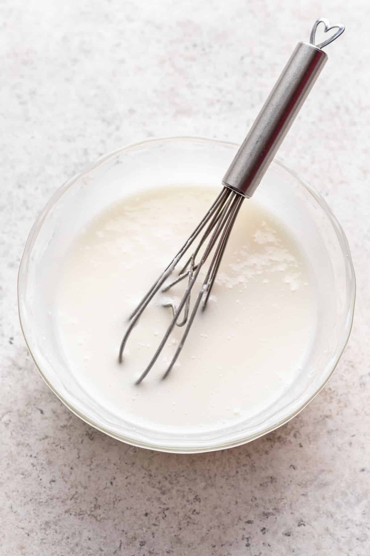 Glaçage dans un bol à mélanger blanc avec un fouet.