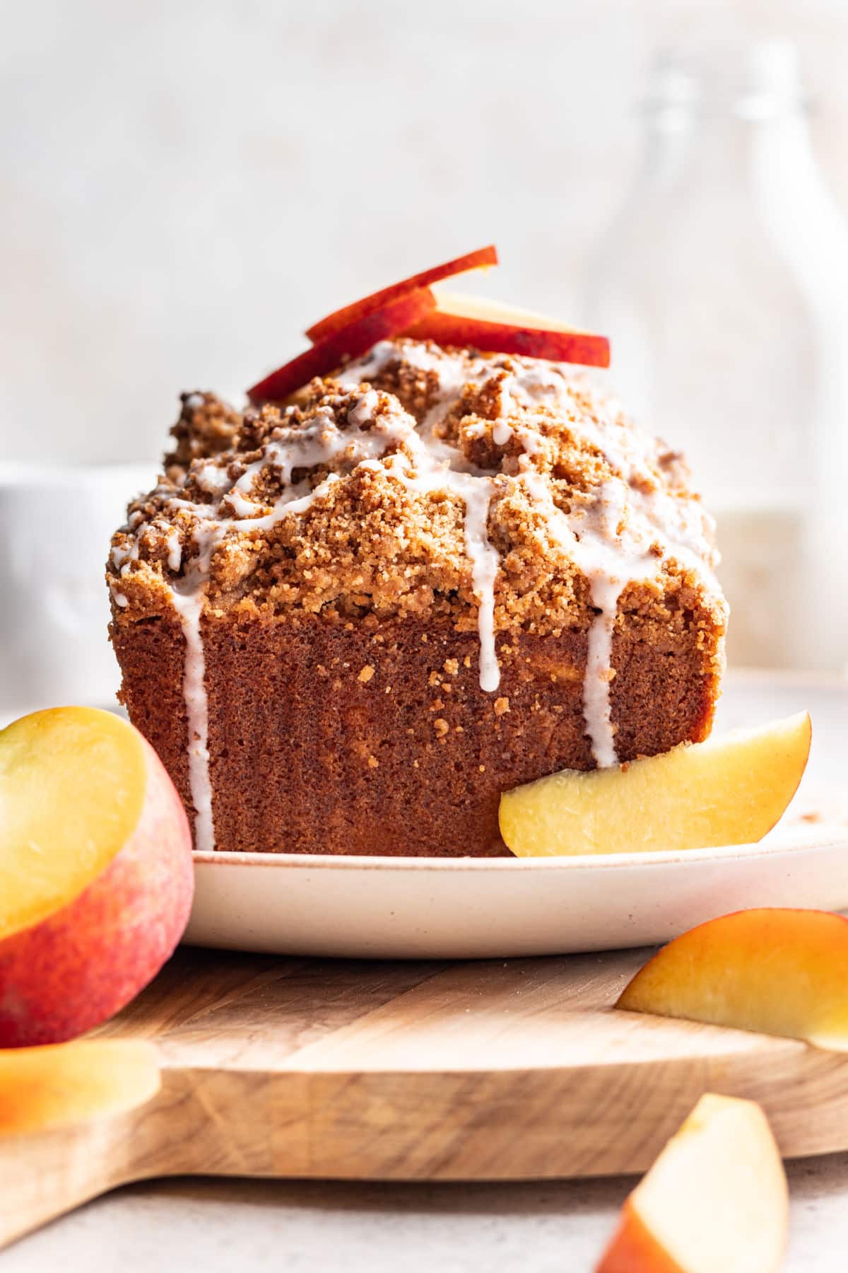 Peach cobbler cake on a white plate topped with two fresh peach slices.