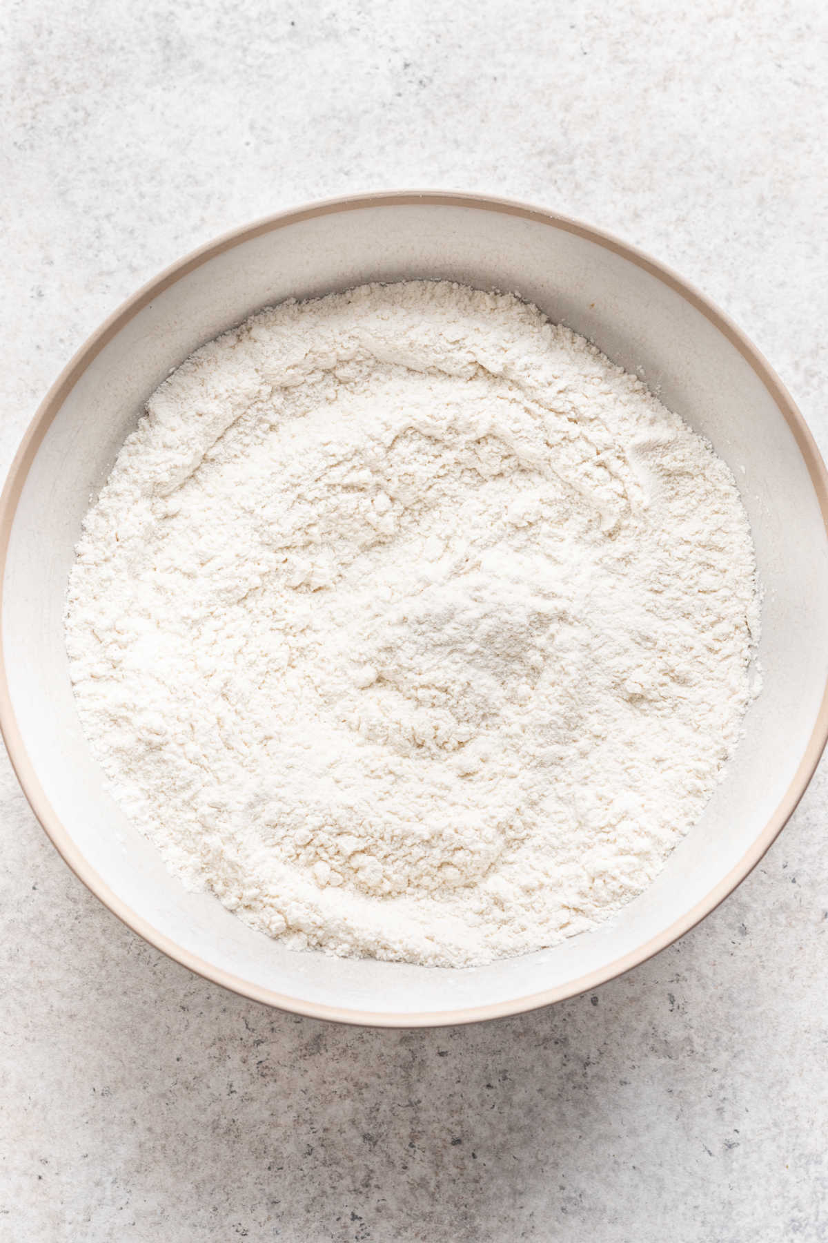Ingrédients secs pour le gâteau aux pêches dans un bol à mélanger blanc.