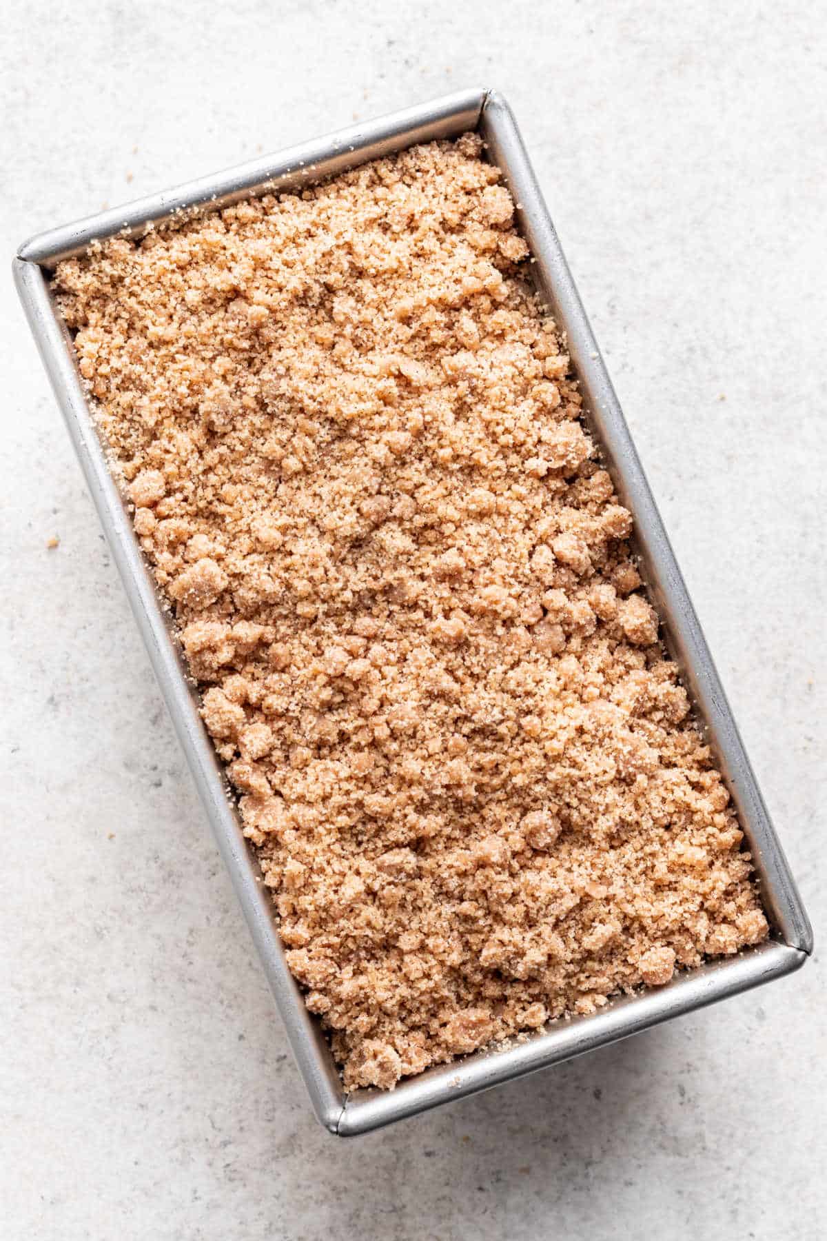 Garniture de crumble sur la pâte à gâteau dans un moule à cake.