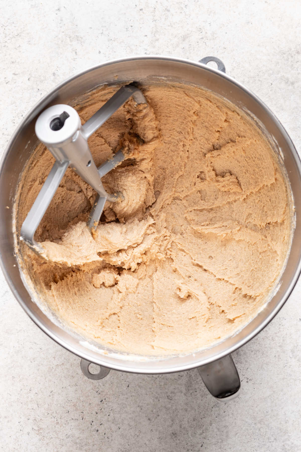 Butter and sugar creamed together in a silver mixing bowl.