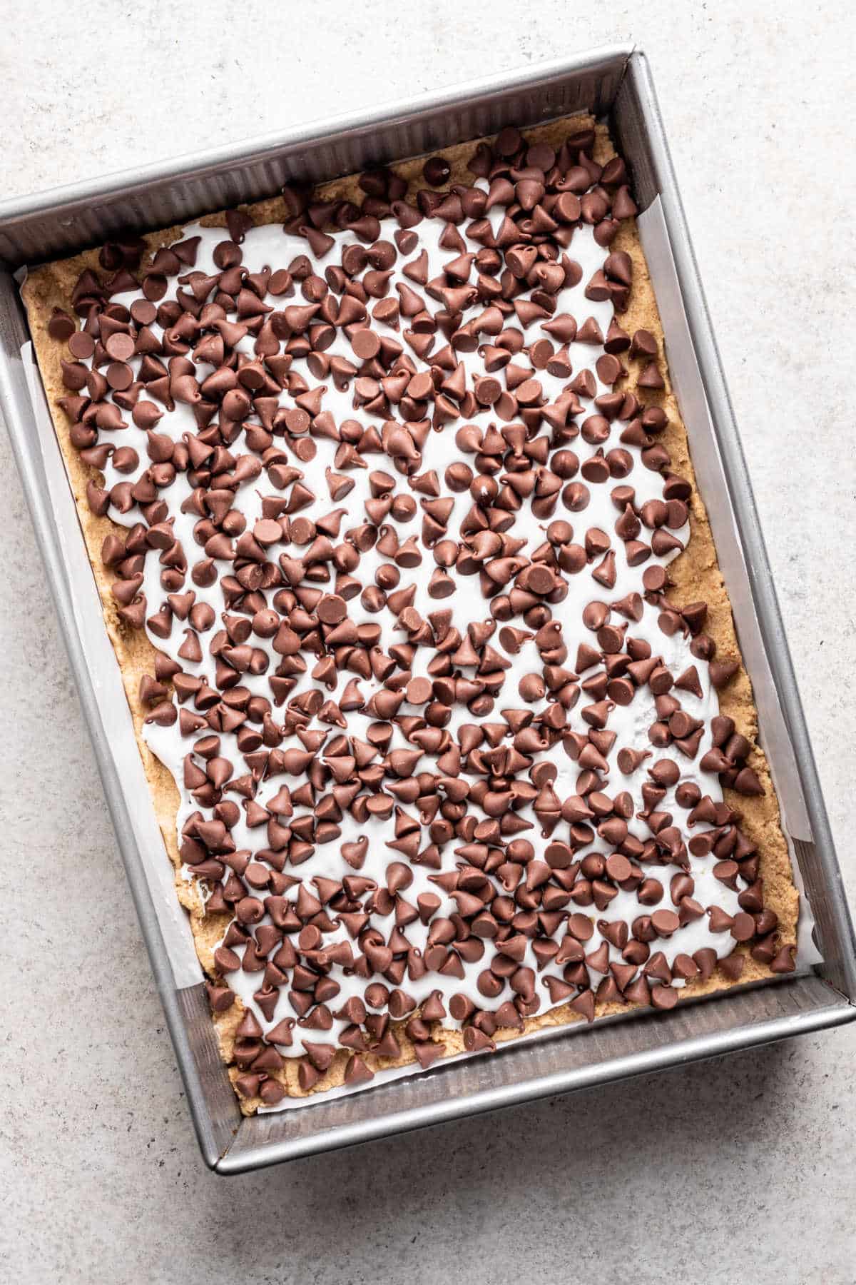 Marshmallow creme and chocolate chips sprinkled over graham cracker dough.
