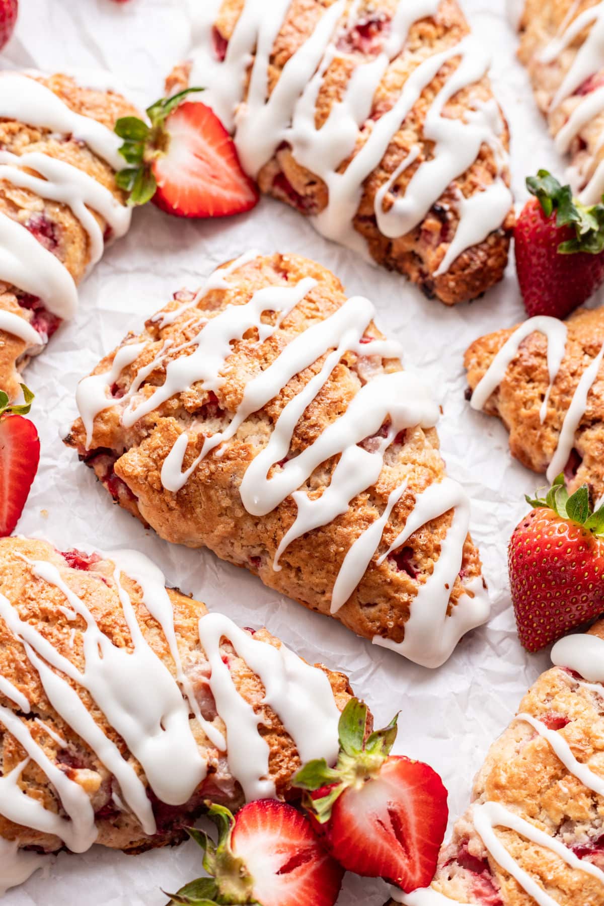 Strawberry scones surrounded by fresh cut strawberries.