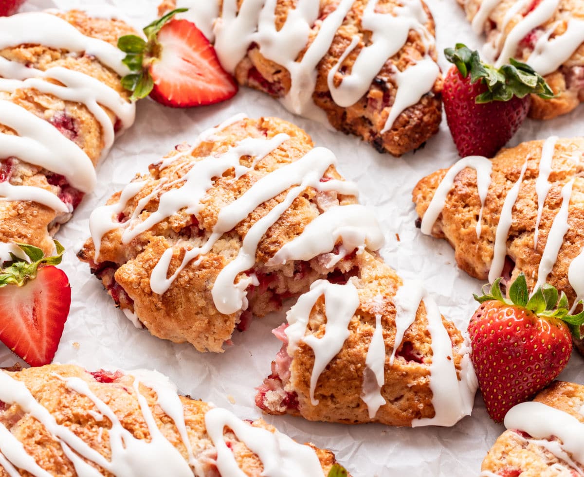 A strawberry scone broken in half in the middle of more scones.