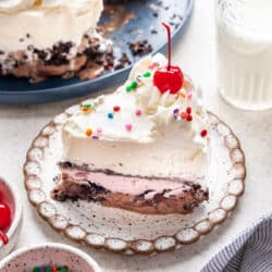 A slice of homemade ice cream cake on a plate next to the cake.