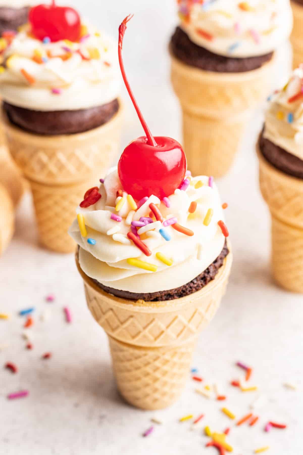 Ice cream cone cupcake surrounded by sprinkles. 