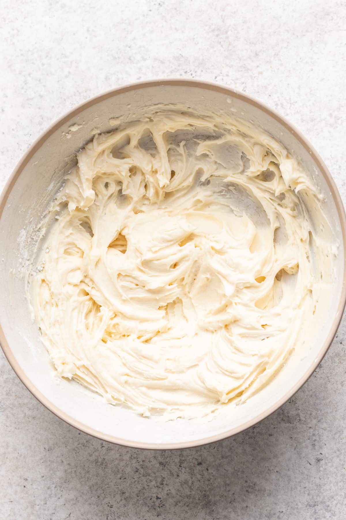 Vanilla buttercream frosting in a white mixing bowl. 