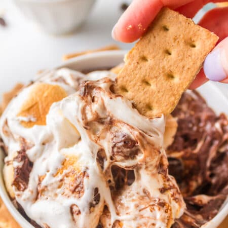 A graham cracker dipping s'mores dip in a white bowl.