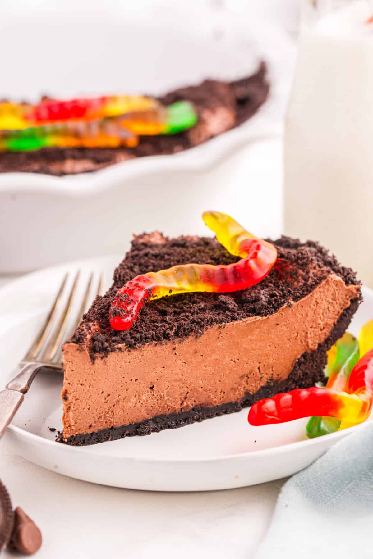 A slice of dirt pie on a white plate next to the pie.