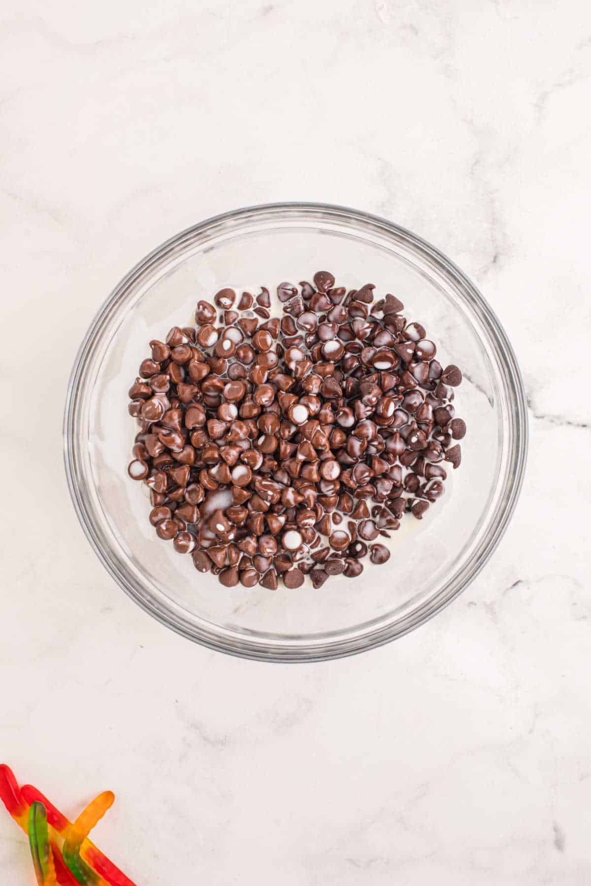 Chocolate chips and cream in a glass mixing bowl.