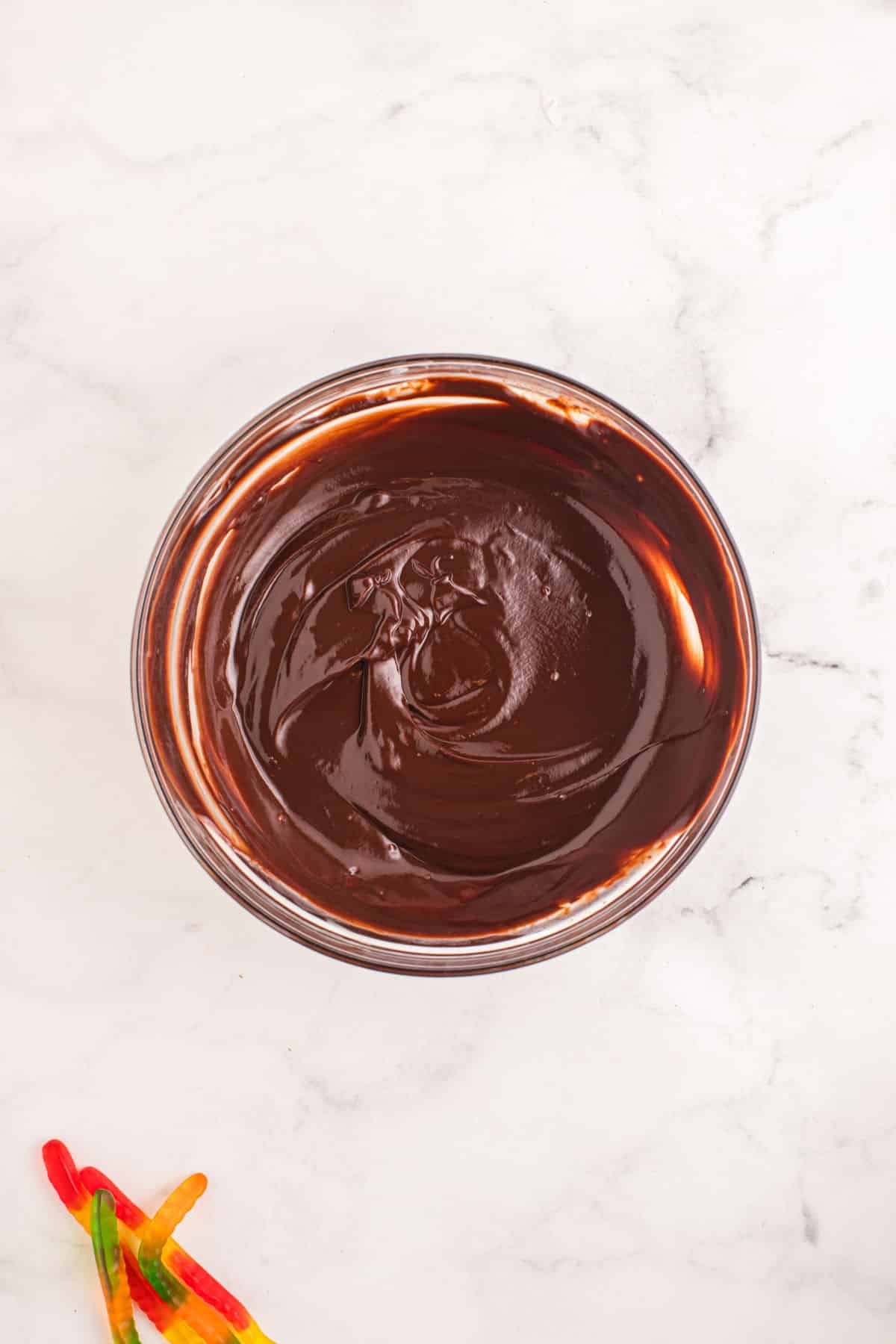 Melted chocolate chip and cream mixture in a glass mixing bowl.
