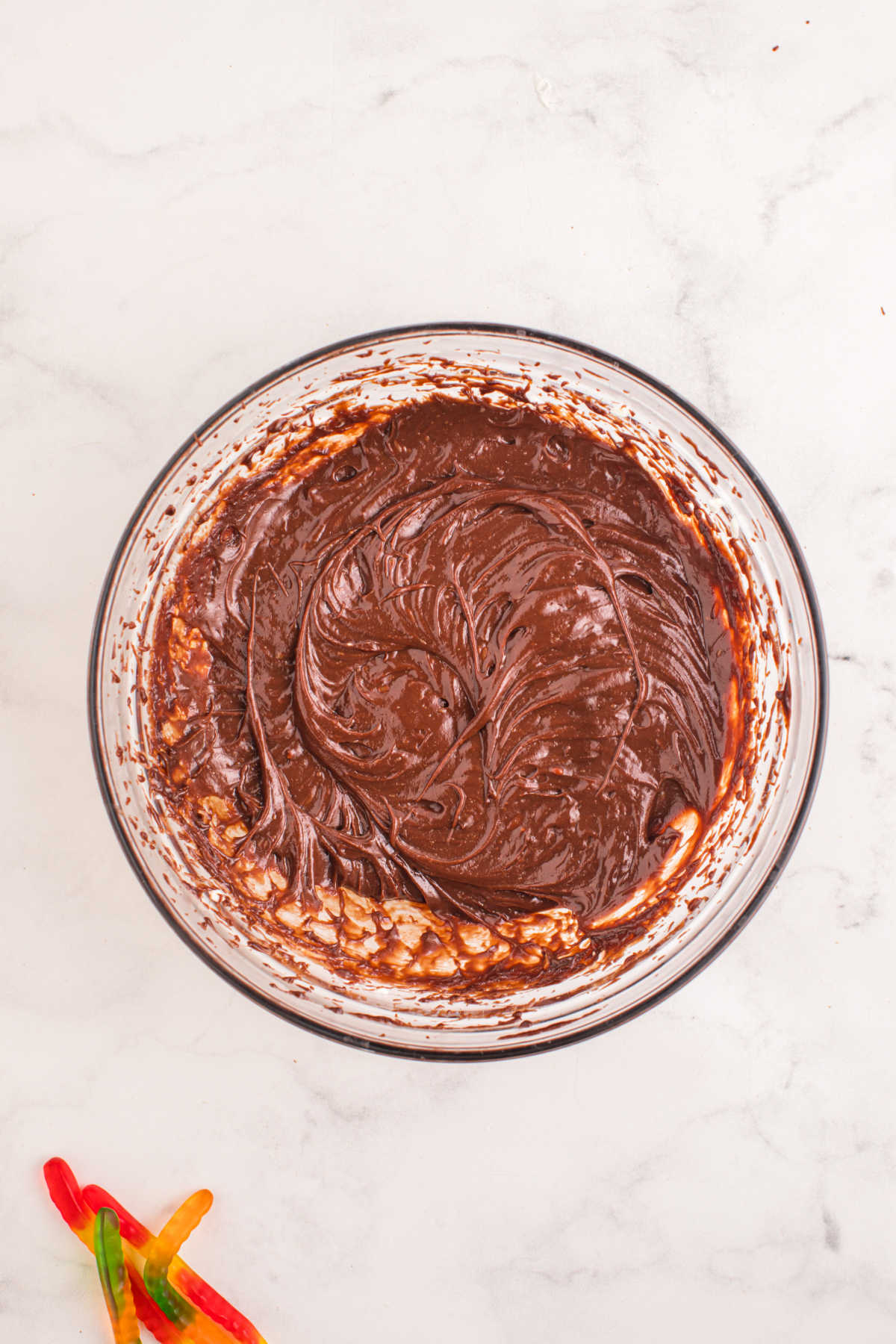 Chocolate cream cheese mixture in a glass mixing bowl.