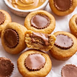 Half of a peanut butter cup cookie leaning against more cookies.
