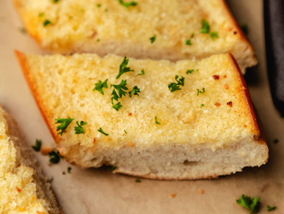 Slices of homemade garlic bread topped with fresh parsley.