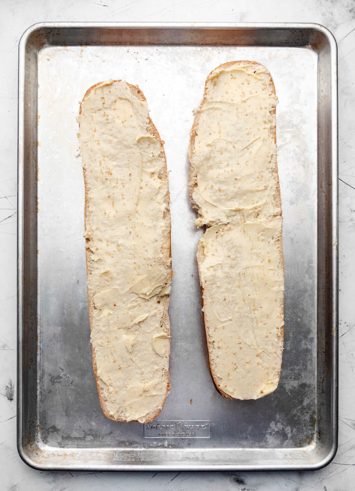 Two pieces of French bread spread with garlic butter.